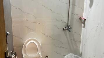 A bathroom with a toilet, shower, and a clear plastic water container.