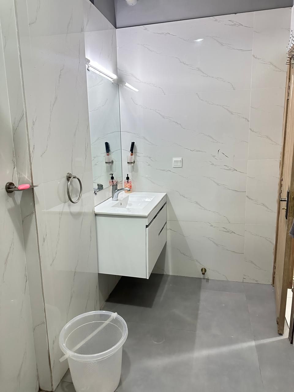 A bathroom with a white marble wall, a sink with a mirror, and a door with a handle.