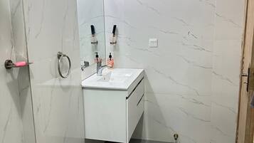 A bathroom with a white marble wall, a sink with a mirror, and a door with a handle.