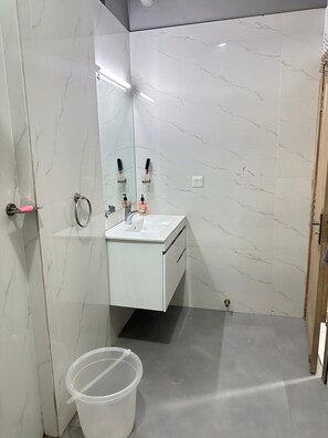 A bathroom with a white marble wall, a sink with a mirror, and a door with a handle. - Perfect 2-bedroom apartment in enchanting Lahore neighborhood (Lahore)