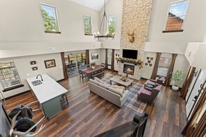 A spacious living area with a fireplace, a dining table, and a kitchen with a sink. - 4 Ensuite Baths | Hot Tub | Pool + Lazy River (Hollister)