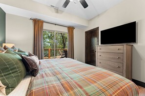 Ein Schlafzimmer mit einem Bett, einer Kommode, einem Fernseher und einem Fenster mit Vorhängen.