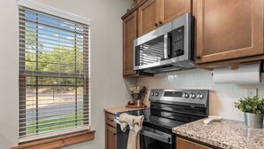 A kitchen with a microwave, oven, and granite countertop. - Oak-Zarks Getaway - Cabin w/ 2 King Suites, Hot Tub, Fire Pit + Resort Amenities (Hollister)