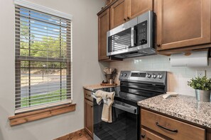 A kitchen with a microwave, oven, and granite countertop. - Oak-Zarks Getaway - Cabin w/ 2 King Suites, Hot Tub, Fire Pit + Resort Amenities (Hollister)