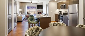 Ein modernes Hotelzimmer mit Küche, Essbereich und Wohnzimmer mit Kamin.