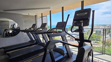 A gym with treadmills and elliptical machines, large windows, and a view of the city.