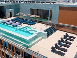 Un área de piscina en la azotea con asientos tipo sillón y una piscina cubierta de cristal.