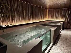 Un área de spa con tres tinas de hidromasaje rectangulares, paneles de pared de bambú y suelo de baldosas.