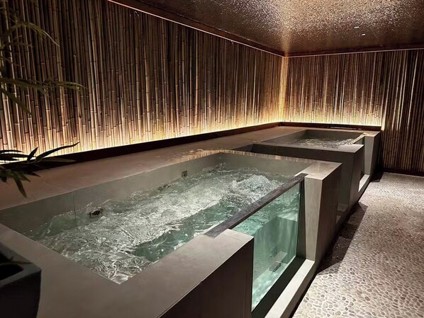 A spa area with three rectangular hot tubs, bamboo wall panels, and a tiled floor.