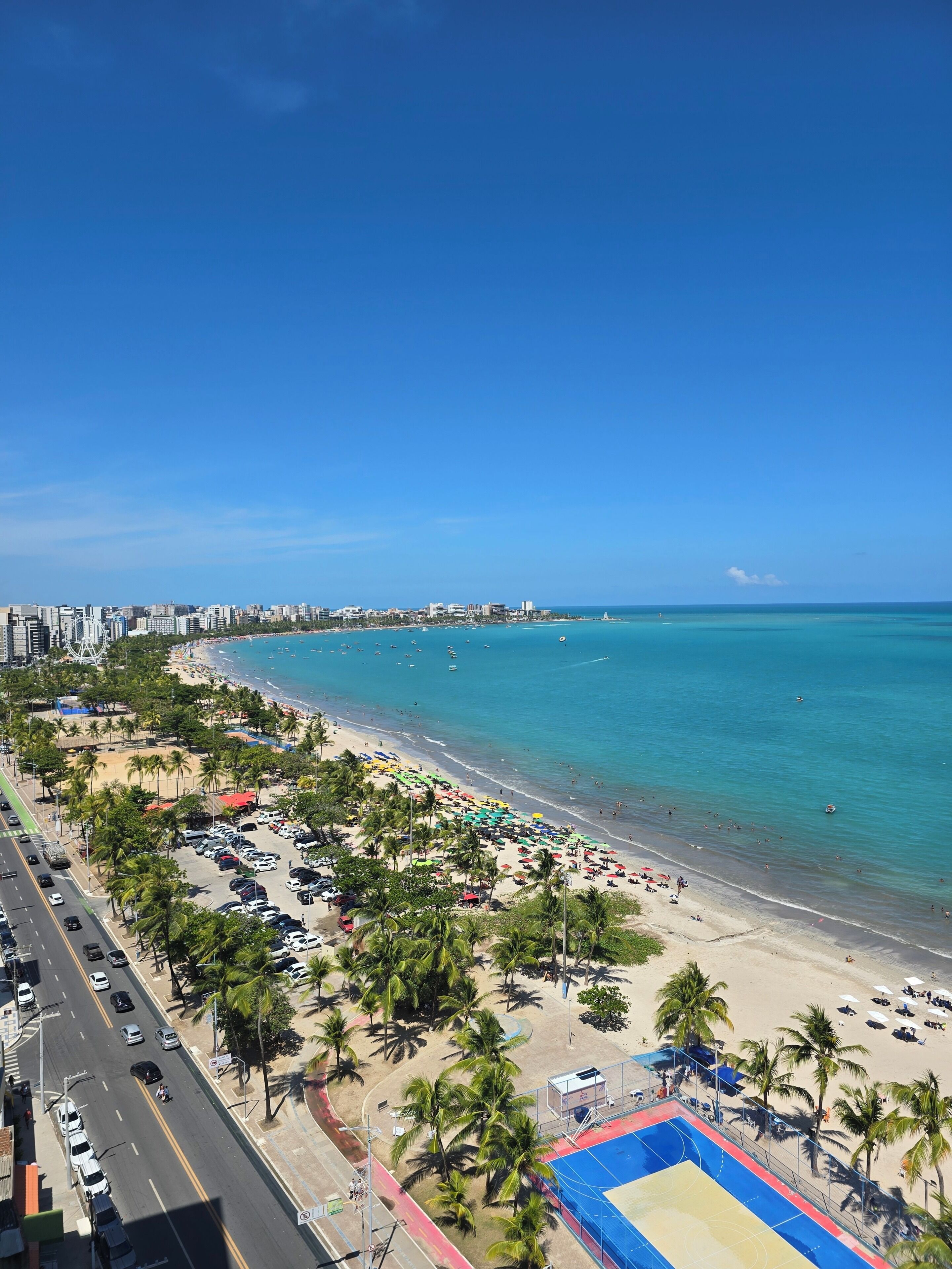 Eine Küstenstadt mit Strand, Palmen und wolkenlosem, blauem Himmel.