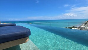 Ein klarer, blauer Himmel, ein Swimmingpool und eine Lounge mit Blick auf den Ozean.