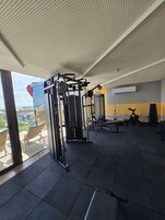 Un gimnasio con equipo de ejercicio, vistas al exterior y una pared con mensajes motivacionales.