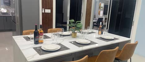 A modern kitchen with a central island, grey cabinets, and a dining area with a white table set for four.