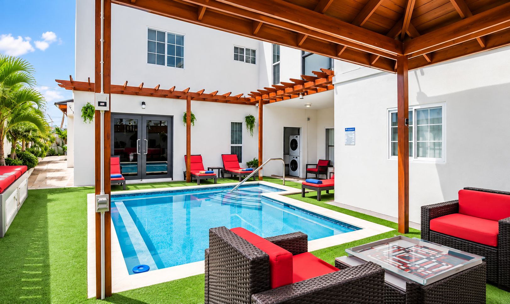 Un espace aménagé au bord de la piscine, comprenant une piscine rectangulaire, des sièges d’extérieur et une pergola couverte.