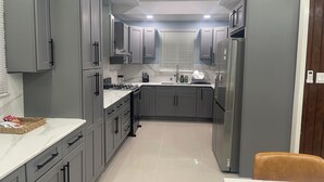 Uma cozinha moderna com armários cinza, uma geladeira de aço inoxidável e bancada de mármore.