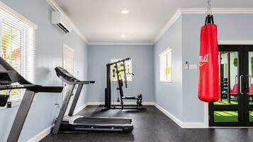 Une salle de sport à domicile équipée d’un tapis de course, d’un banc de musculation et d’un sac de frappe.
