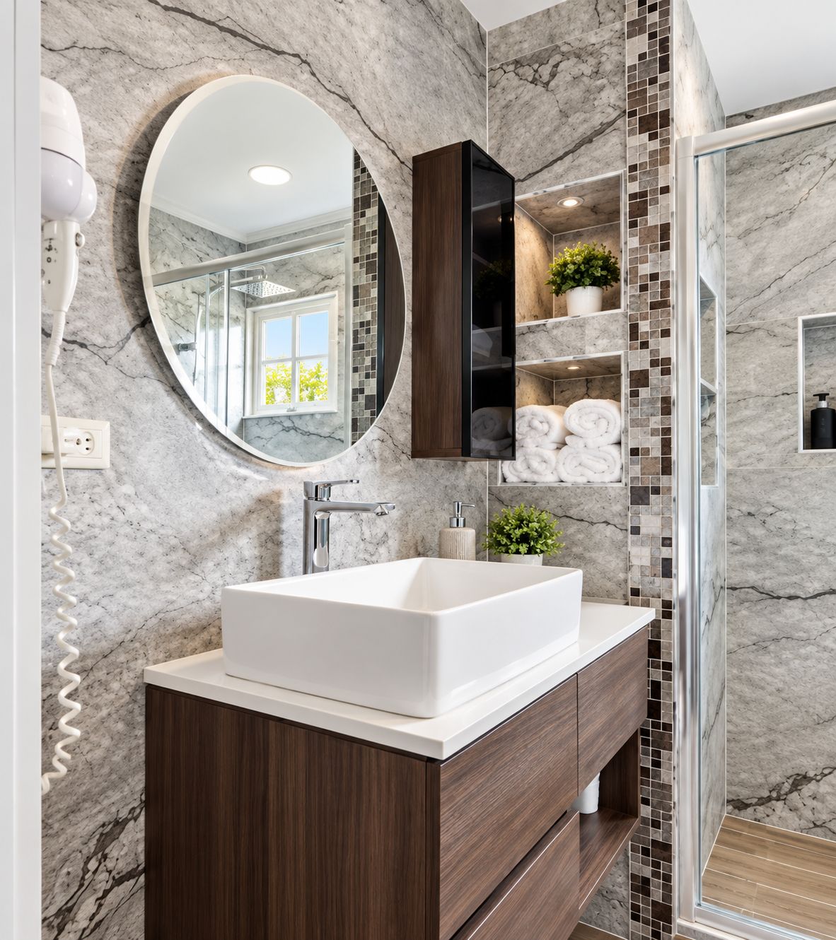 Un bagno con una parete in marmo, un lavandino bianco, uno specchio, una doccia e un portasciugamani.