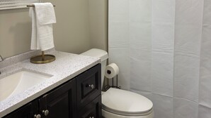 Een badkamer met een witte wastafel, donkere kastjes, een toilet en een douchegordijn.