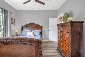 A bedroom with a wooden bed, a dresser, and a ceiling fan.