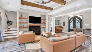 A spacious living room with a fireplace, sofas, a coffee table, and a TV. - Luxury pro golf & equestrian retreat with pool and gym. Peaceful retreat 6BD/4BR (Carthage)