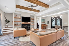 A spacious living room with a fireplace, sofas, a coffee table, and a TV.