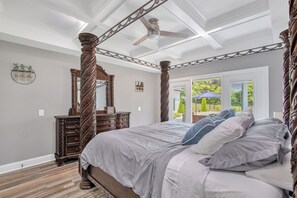 Un dormitorio con cama con dosel, cómoda de madera y ventilador de techo.