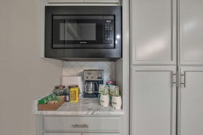 A kitchen with a built-in microwave, coffee maker, and various kitchen items on the counter.