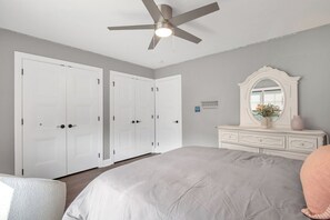 Un dormitorio con cama, cómoda, espejo y ventilador de techo.