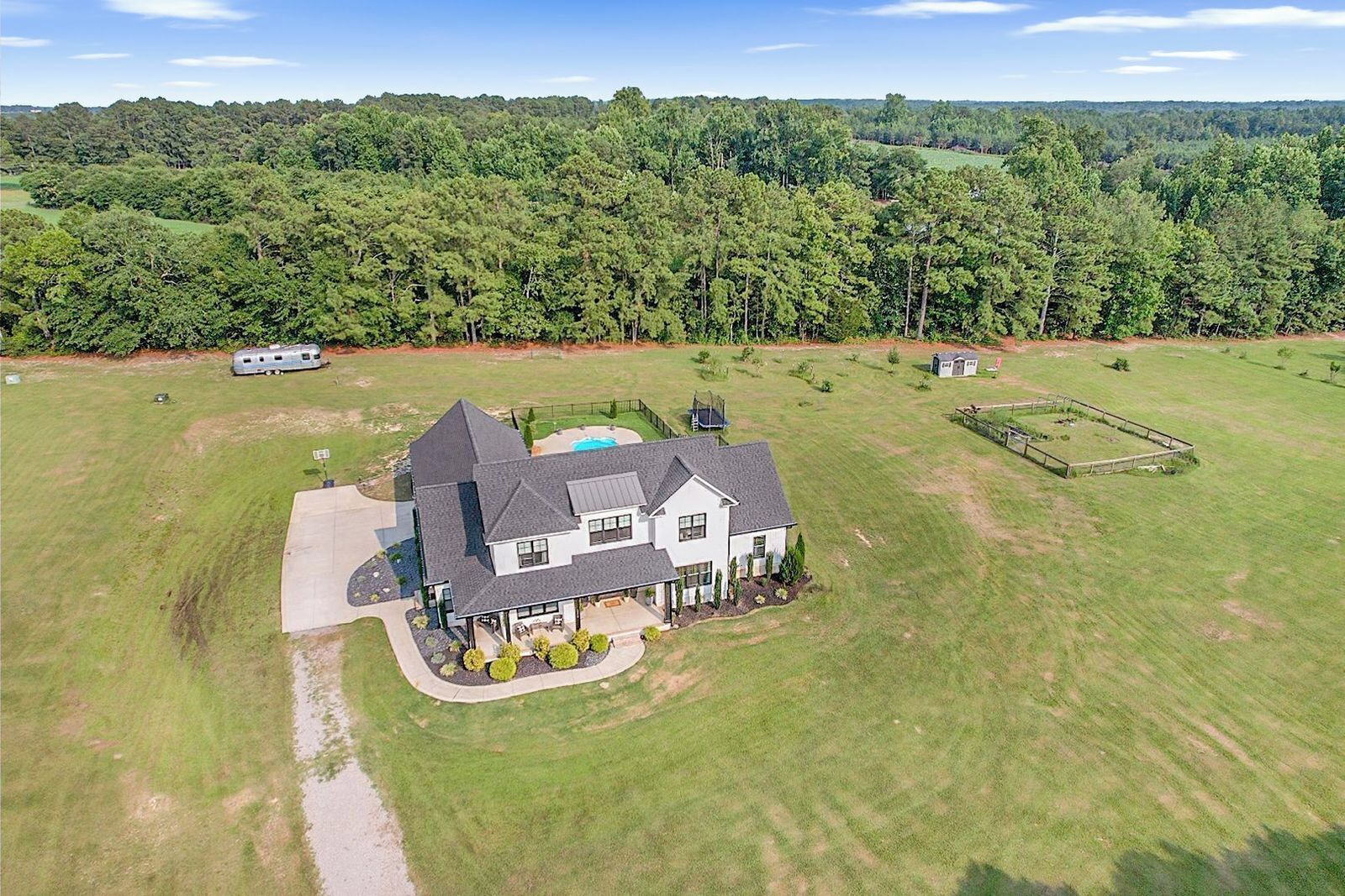 A large house with a spacious lawn, a swimming pool, and a fenced area.