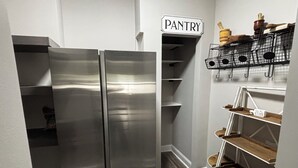 A compact kitchen with a stainless steel refrigerator, a pantry area, and open shelving with kitchenware. - Luxury pro golf & equestrian retreat with pool and gym. Peaceful retreat 6BD/4BR (Carthage)