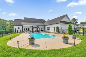 Una propiedad residencial con piscina, un patio cubierto y jardín cercado.