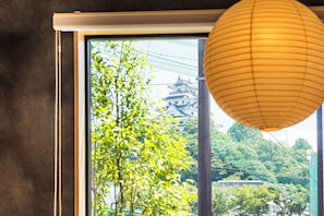 Una ventana con vista a un edificio tradicional y un árbol en primer plano.