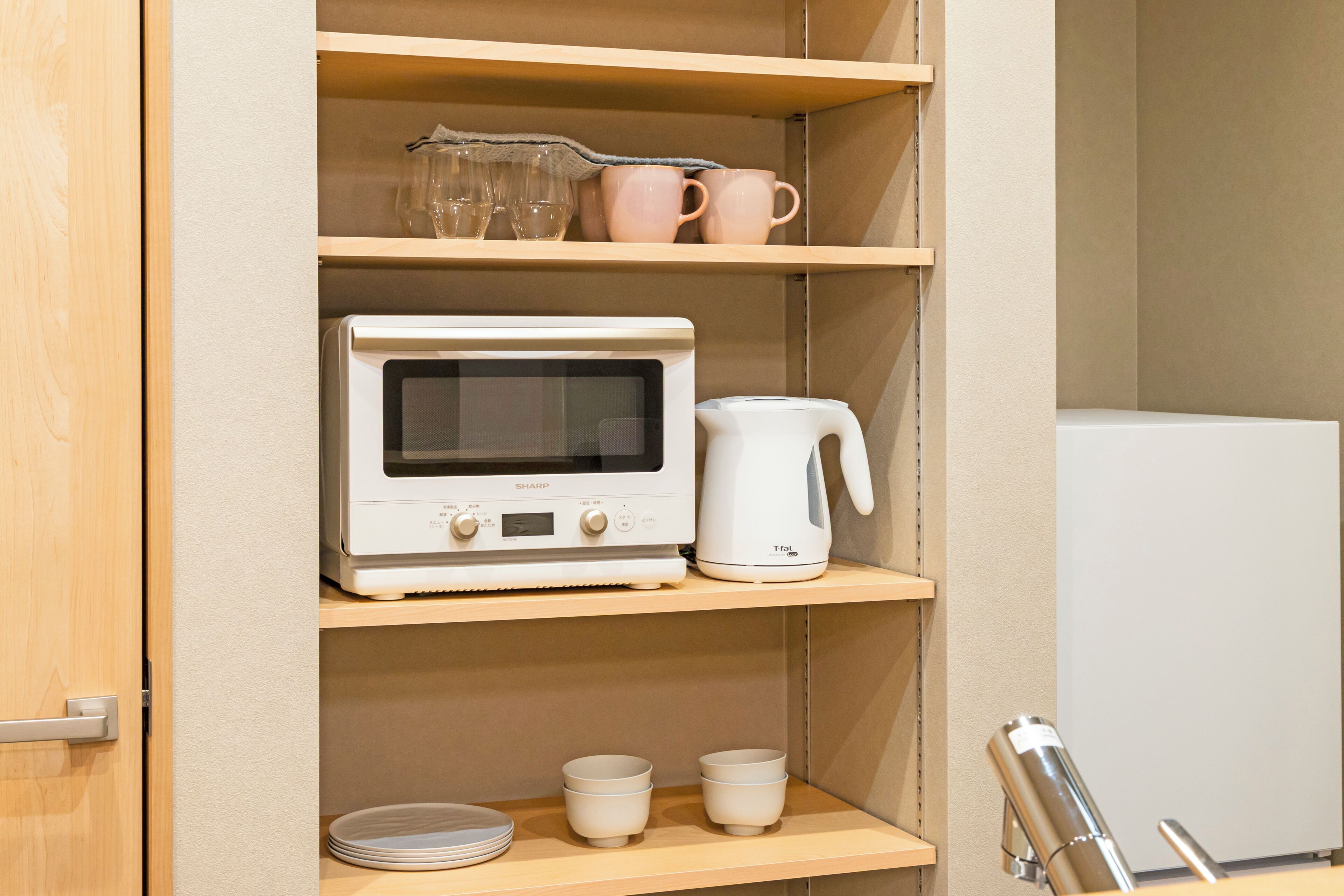 A kitchen with a microwave, a coffee maker, and a refrigerator.