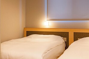 Habitación de hotel con dos camas, cabecera de madera y lámpara de pared.