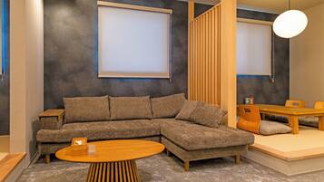 En moderne stue med en krogsofa, et rundt træbord og et spiseområde med et træbord og stole.