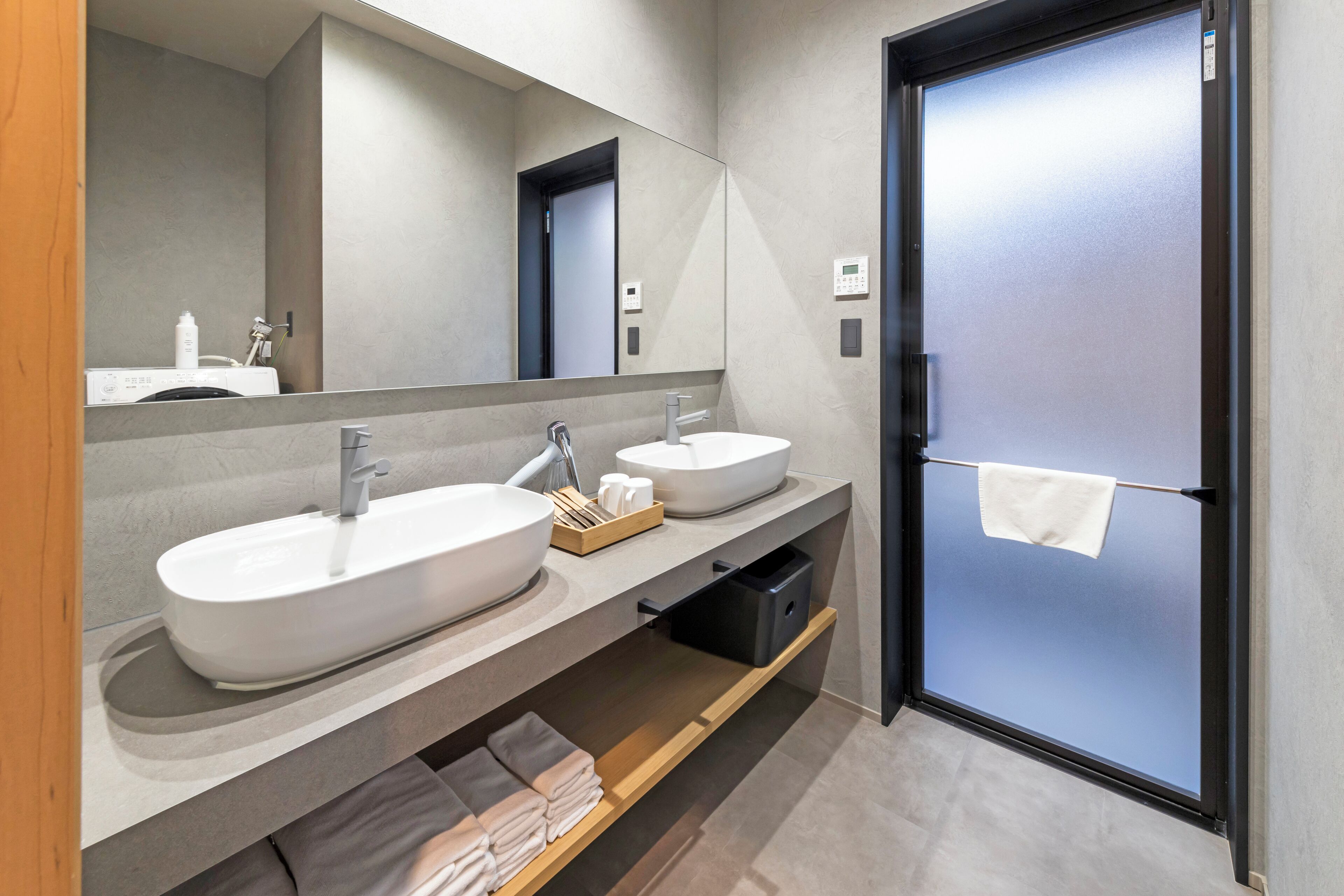 A modern bathroom with two sinks, a mirror, and a towel rack.