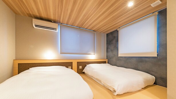 Habitación de hotel con dos camas, techo de madera y ventana con vistas.