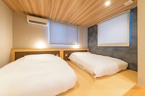 Habitación de hotel con dos camas, techo de madera y ventana con vistas.