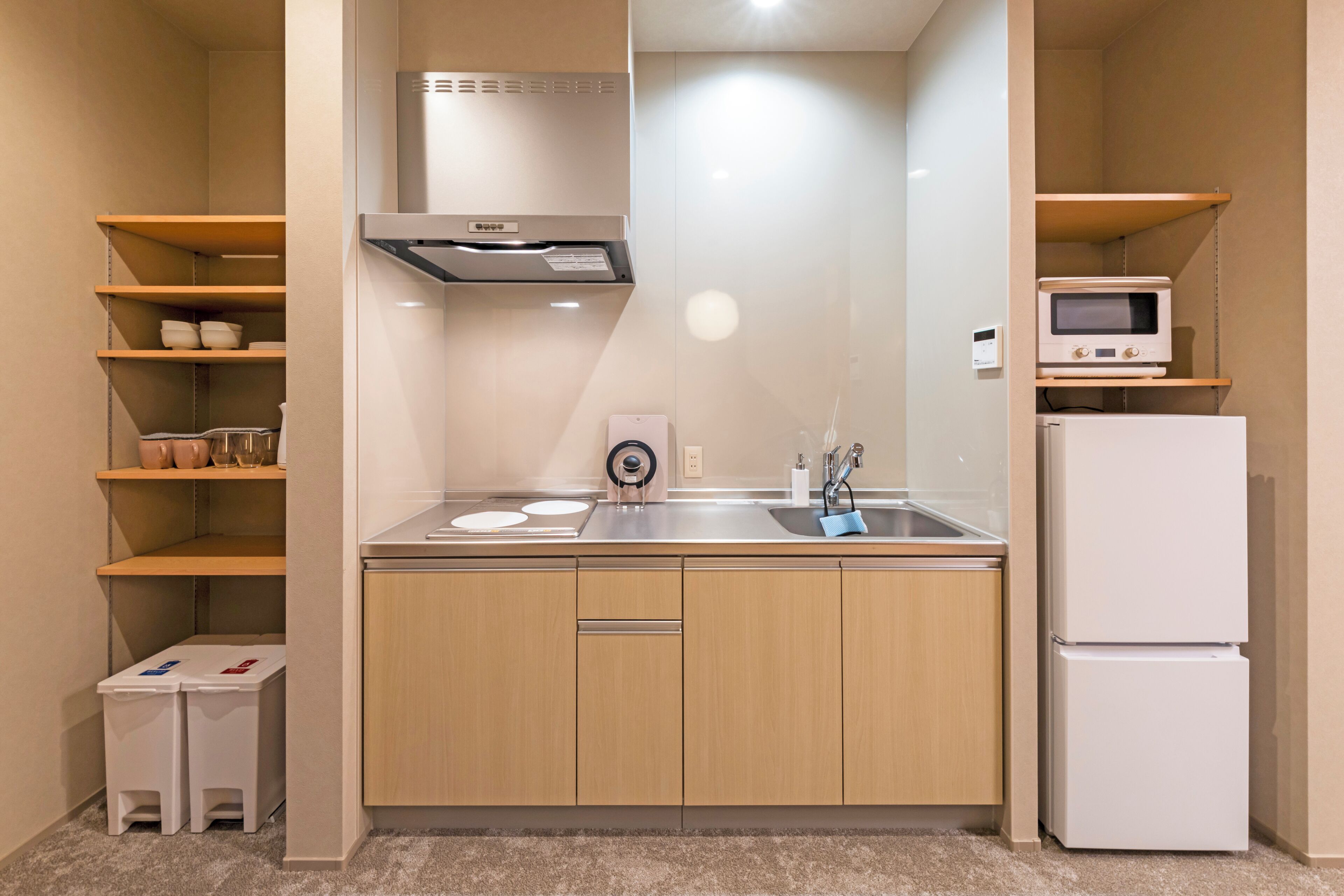 A compact kitchen with a microwave, refrigerator, sink, and cabinets.
