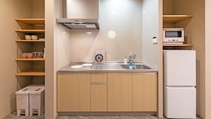 A compact kitchen with a microwave, refrigerator, sink, and cabinets.