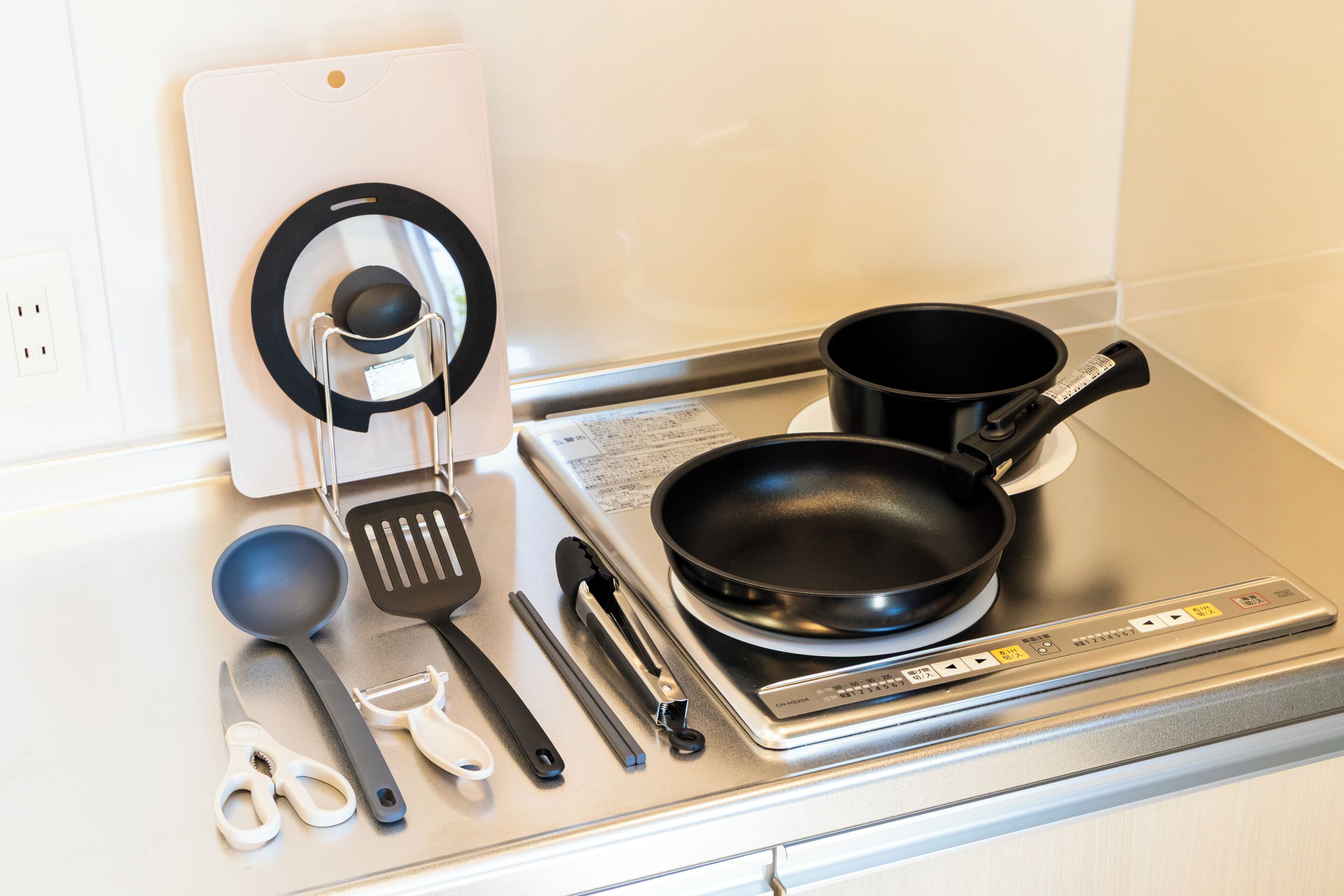 Uma cozinha com fogão, panelas, espátula e diversos utensílios.