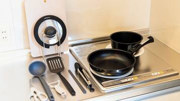 Uma cozinha com fogão, panelas, espátula e diversos utensílios.