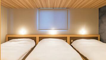 Une chambre d’hôtel avec deux lits, un plafond en bois et un luminaire fixé au mur.