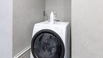 Una lavadora de carga frontal con panel de control y mangueras de entrada de agua.