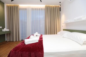 A hotel room with a bed, a red throw blanket, a white pillow, and a window with curtains. - Palm Olive Studio (Orikum)
