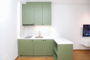 A compact kitchen with a white countertop, green cabinets, and a built-in dishwasher. - Palm Olive Studio (Orikum)
