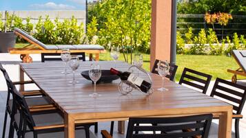 An outdoor dining area with a wooden table, black chairs, and wine glasses.
