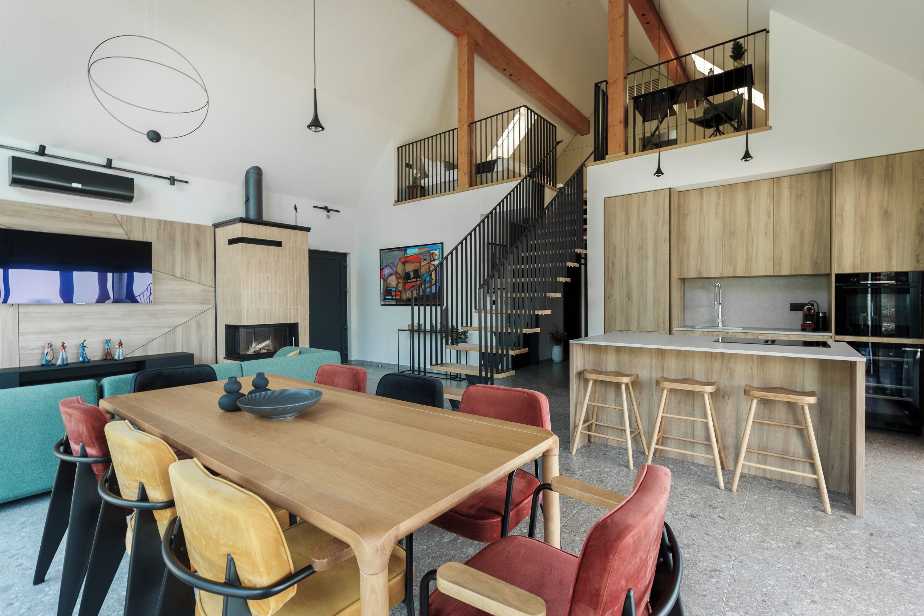 Une cuisine moderne avec des meubles en bois, un îlot central doté de tabourets et un coin repas avec une table et des chaises en bois.