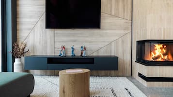 Una sala de estar moderna con un televisor de pantalla plana montado en una pared de madera, una chimenea empotrada y un mueble de entretenimiento minimalista.