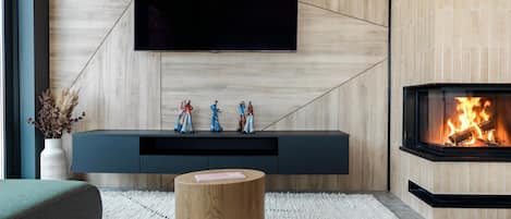 Una sala de estar moderna con un televisor de pantalla plana montado en una pared de madera, una chimenea empotrada y un mueble de entretenimiento minimalista.